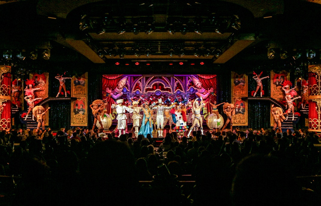 Performers on stage at the Moulin Rouge show in Paris, featuring vibrant costumes and elaborate set design.