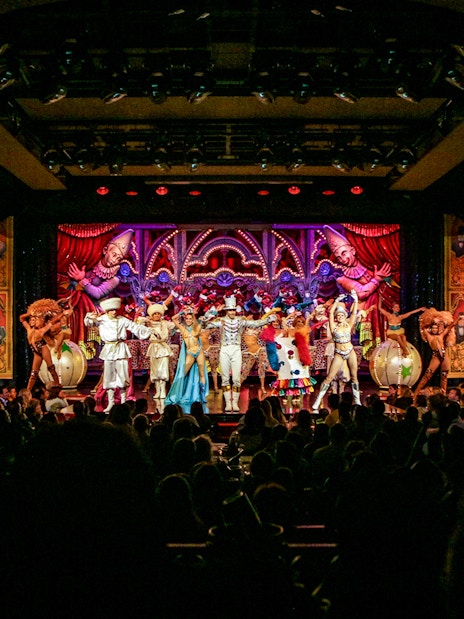 Performers on stage at the Moulin Rouge show in Paris, featuring vibrant costumes and elaborate set design.