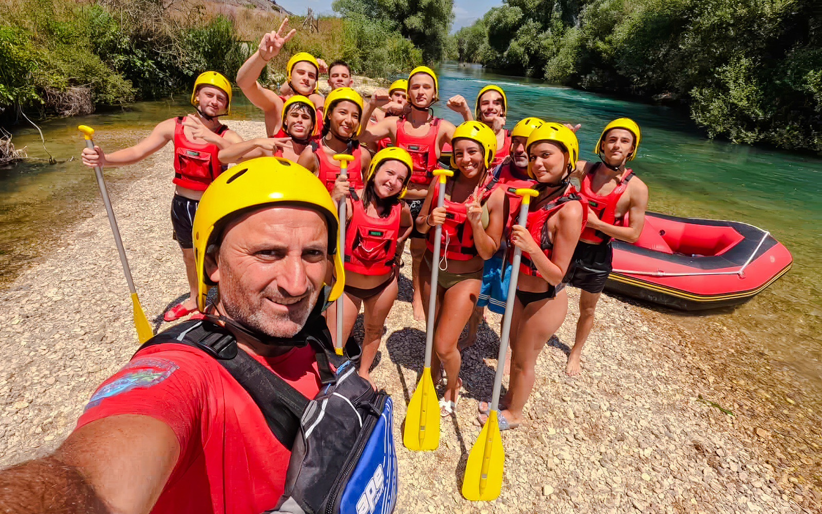 Group ready for Bistrice River rafting adventure near Saranda, holding paddles by the riverbank.
