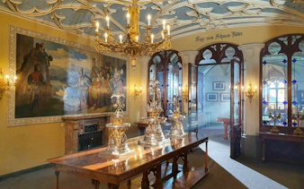Hohenschwangau Castle interior with ornate chandelier, mural, and decorative silverware in Bavaria.