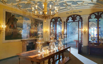 Hohenschwangau Castle interior with ornate chandelier, mural, and decorative silverware in Bavaria.