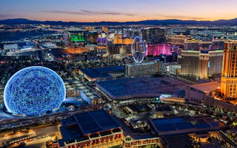 Las Vegas skyline at dusk with illuminated Sphere and Ferris wheel, view from helicopter tour.