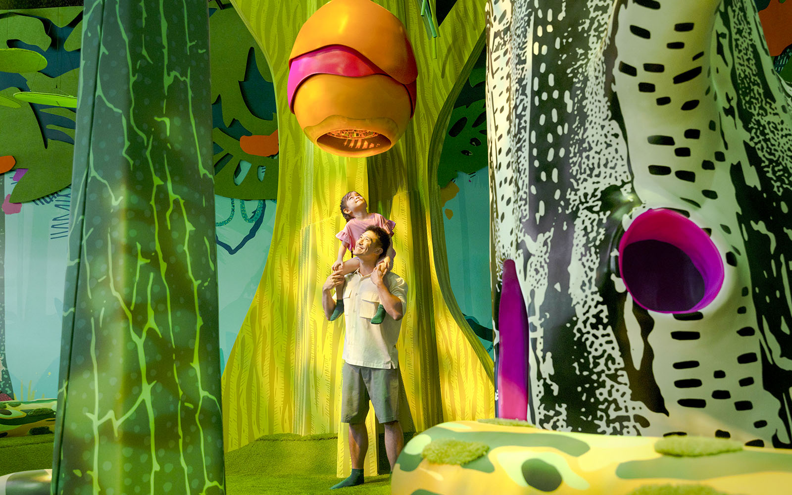 Father and child exploring Curiosity Cove&#x27;s vibrant bee hive exhibit.