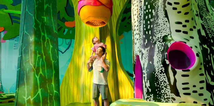 Father and child exploring Curiosity Cove's vibrant bee hive exhibit.