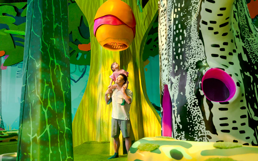 Father and child exploring Curiosity Cove's vibrant bee hive exhibit.