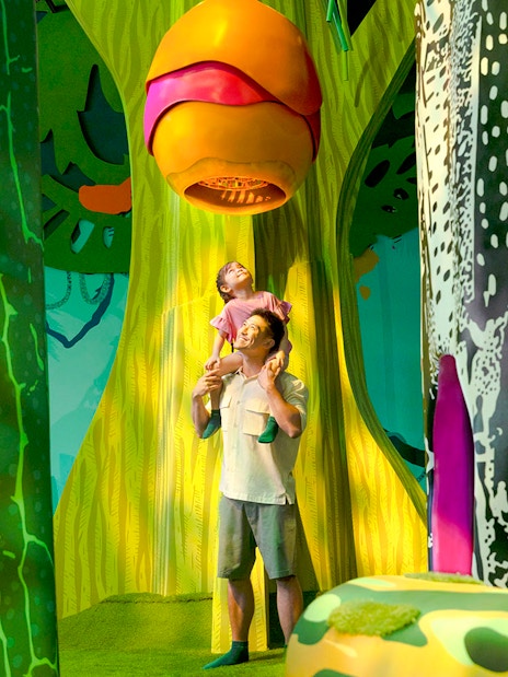 Father and child exploring Curiosity Cove's vibrant bee hive exhibit.