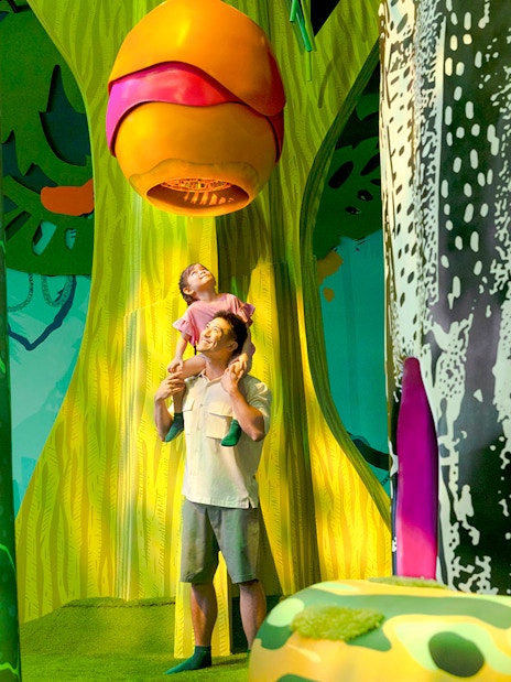 Father and child exploring Curiosity Cove's vibrant bee hive exhibit.