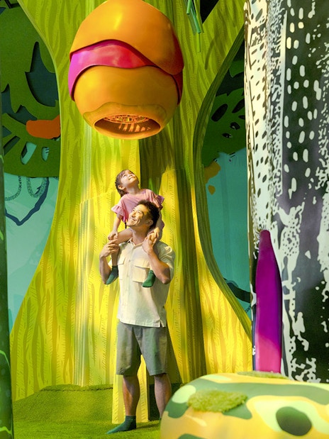 Father and child exploring Curiosity Cove's vibrant bee hive exhibit.