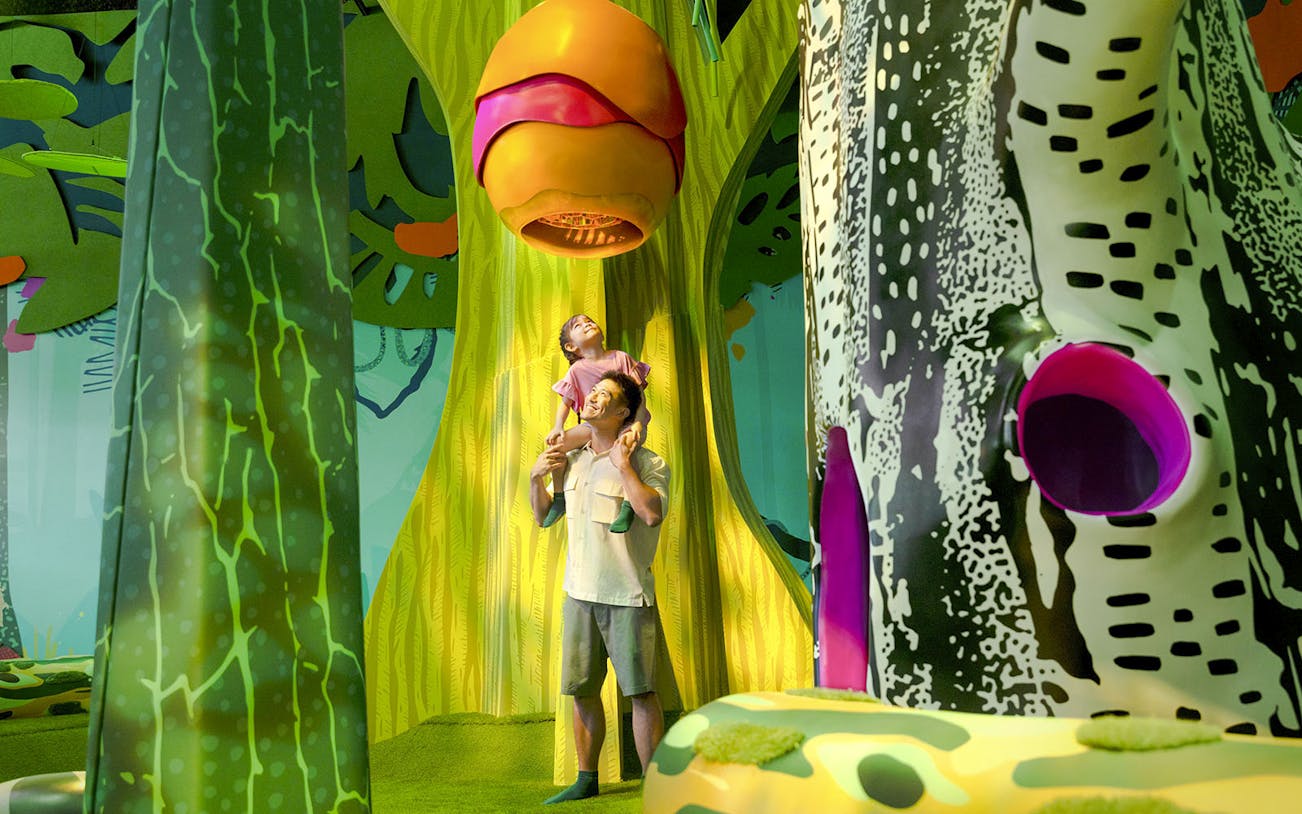 Father and child exploring Curiosity Cove's vibrant bee hive exhibit.