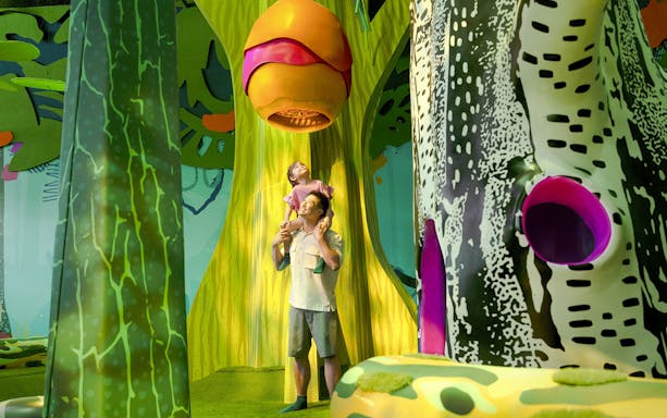 Father and child exploring Curiosity Cove's vibrant bee hive exhibit.