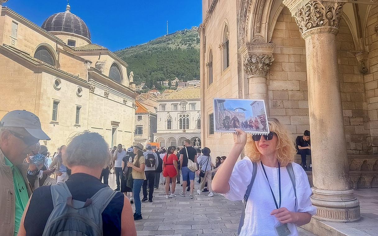 Female guide showing Game of Thrones location to tourists in Dubrovnik, Croatia.