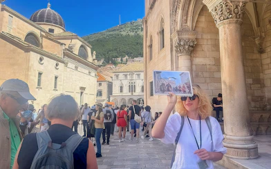 Female guide showing Game of Thrones location to tourists in Dubrovnik, Croatia.