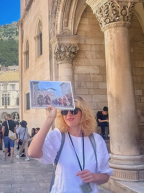 Female guide showing Game of Thrones location to tourists in Dubrovnik, Croatia.