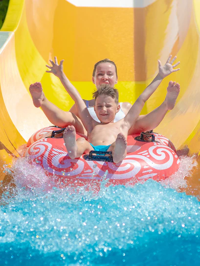 Child and adult on a water slide at Aquafan Water Park, Rimini.