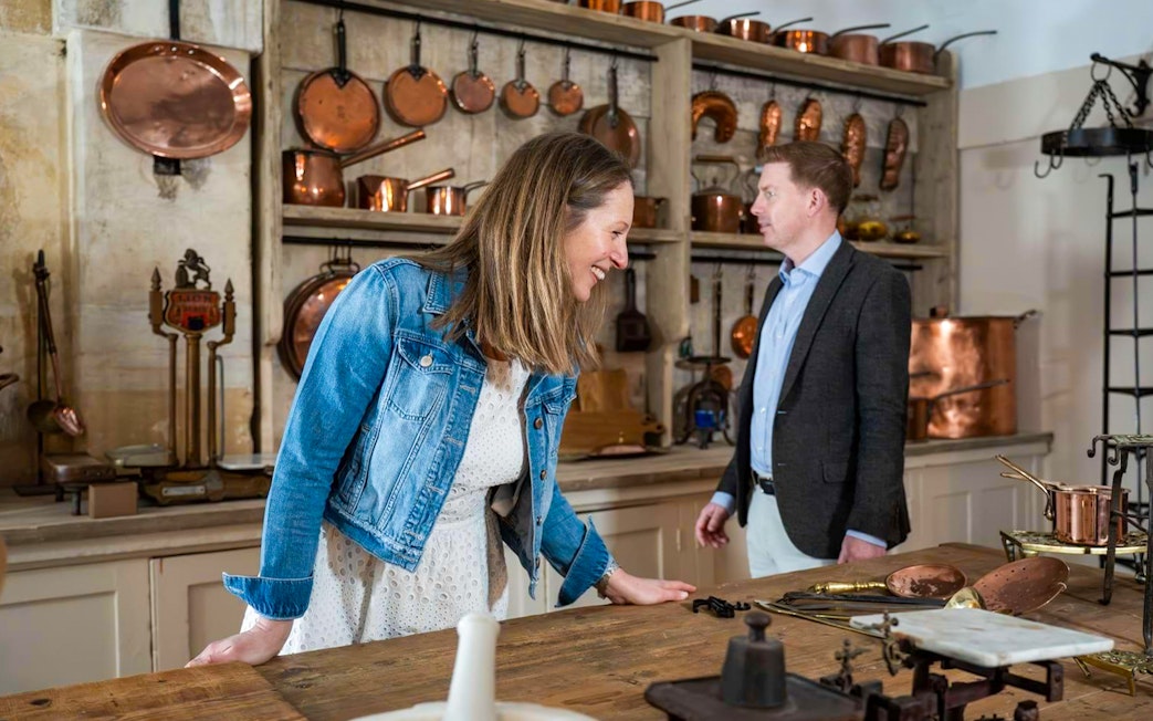 Visitors exploring the kitchen at Blenheim Palace with copper cookware displayed.