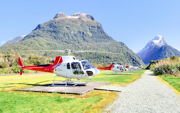 Helicopters on landing pads with Milford Sound mountains in the background.