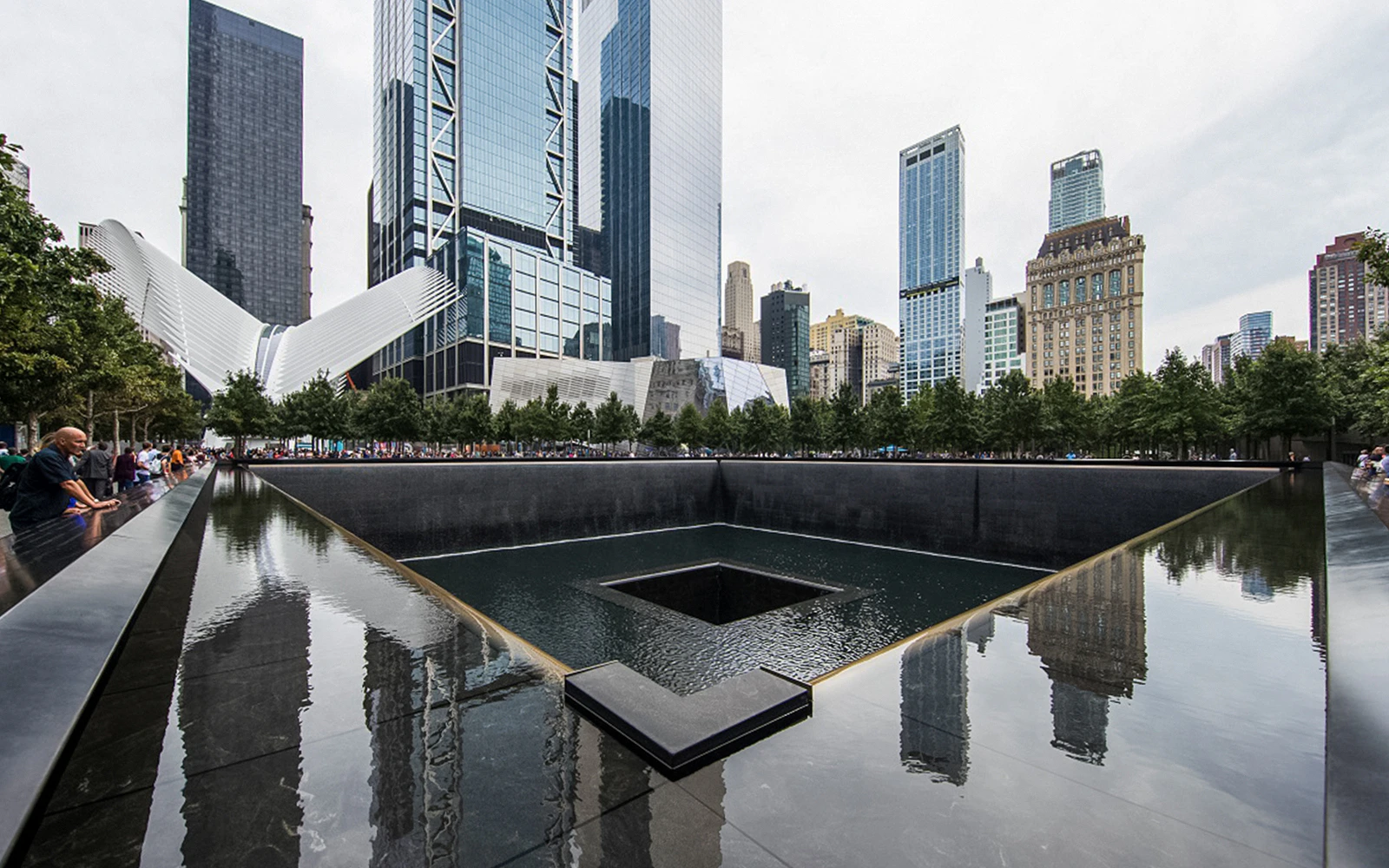 9/11 Memorial waterfall with city skyline in the evening, New York City.
