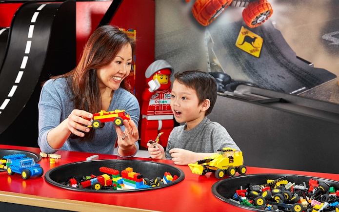 Child and adult building LEGO cars at indoor playground, LEGOLAND Discovery Centre Berlin.