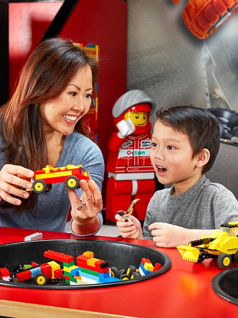 Child and adult building LEGO cars at indoor playground, LEGOLAND Discovery Centre Berlin.