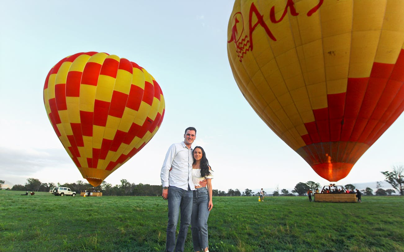 Couple standing near hot air balloons ready for a luxury flight experience.