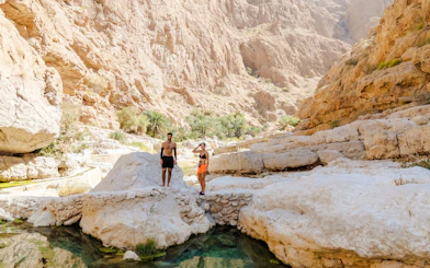 Tourists exploring rocky landscape at Wadi Shab, Oman.