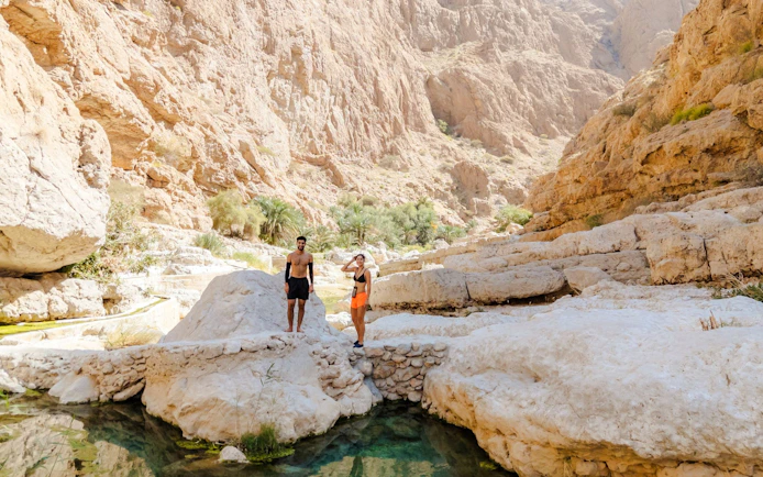 Tourists exploring rocky landscape at Wadi Shab, Oman.