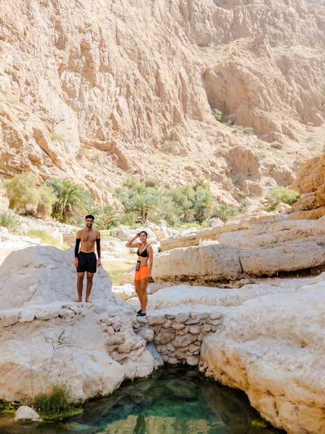Tourists exploring rocky landscape at Wadi Shab, Oman.