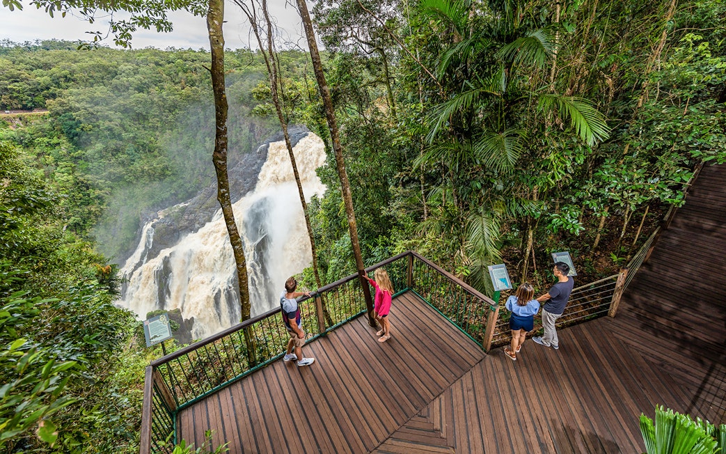 Visitors at a Kuranda lookout point viewing a waterfall amidst lush rainforest.