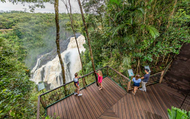 Visitors at a Kuranda lookout point viewing a waterfall amidst lush rainforest.