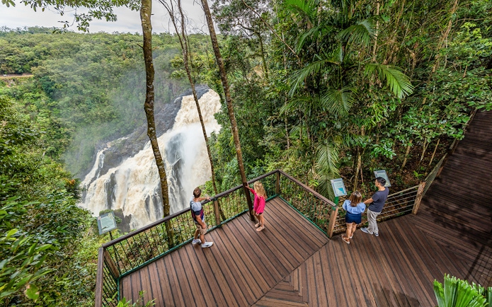 Visitors at a Kuranda lookout point viewing a waterfall amidst lush rainforest.