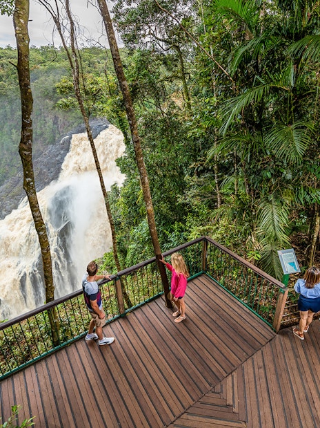 Visitors at a Kuranda lookout point viewing a waterfall amidst lush rainforest.