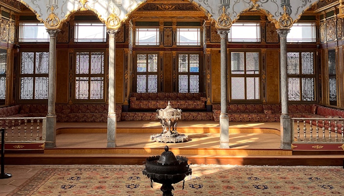 Visitors exploring the historic Topkapi Palace Museum courtyard in Istanbul.