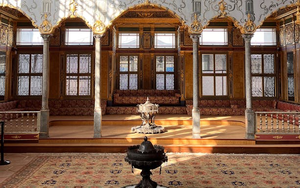 Interior of Topkapi Palace Museum with ornate columns and decorative windows.