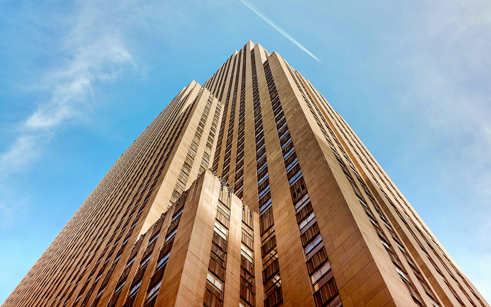 Rockefeller Center skyscraper viewed from below against blue sky.