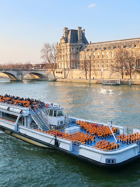 Cruise boat on the Seine River passing by the Louvre Palace in Paris.