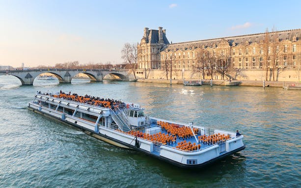 Cruise boat on the Seine River passing by the Louvre Palace in Paris.