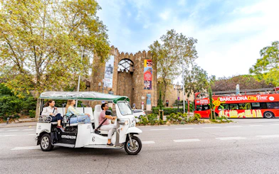 Tuk tuk tour passing by Poble Espanyol entrance in Barcelona.