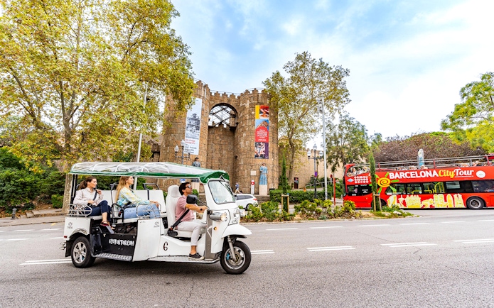 Tuk tuk tour passing by Poble Espanyol entrance in Barcelona.