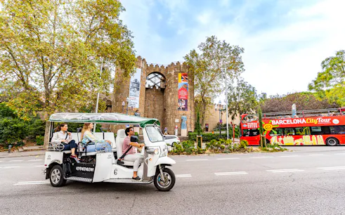 Tuk tuk tour passing by Poble Espanyol entrance in Barcelona.