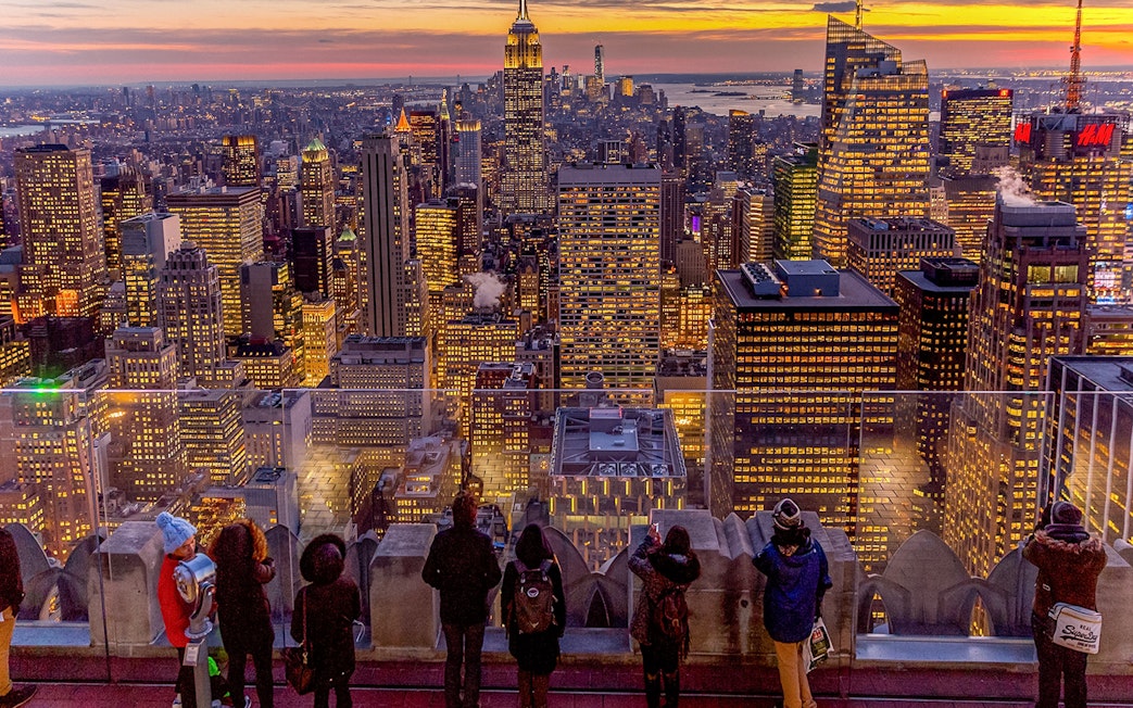 Visitors viewing Manhattan skyline at sunset from Top of the Rock, Rockefeller Center, New York.