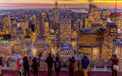 Visitors viewing Manhattan skyline at sunset from Top of the Rock, Rockefeller Center, New York.