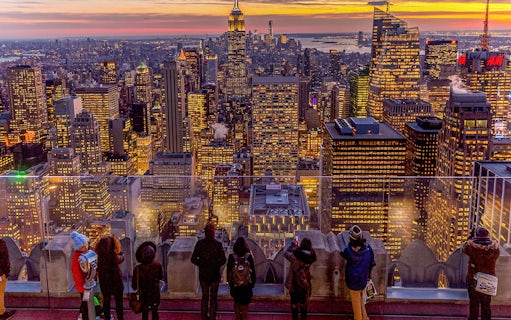 Visitors viewing Manhattan skyline at sunset from Top of the Rock, Rockefeller Center, New York.