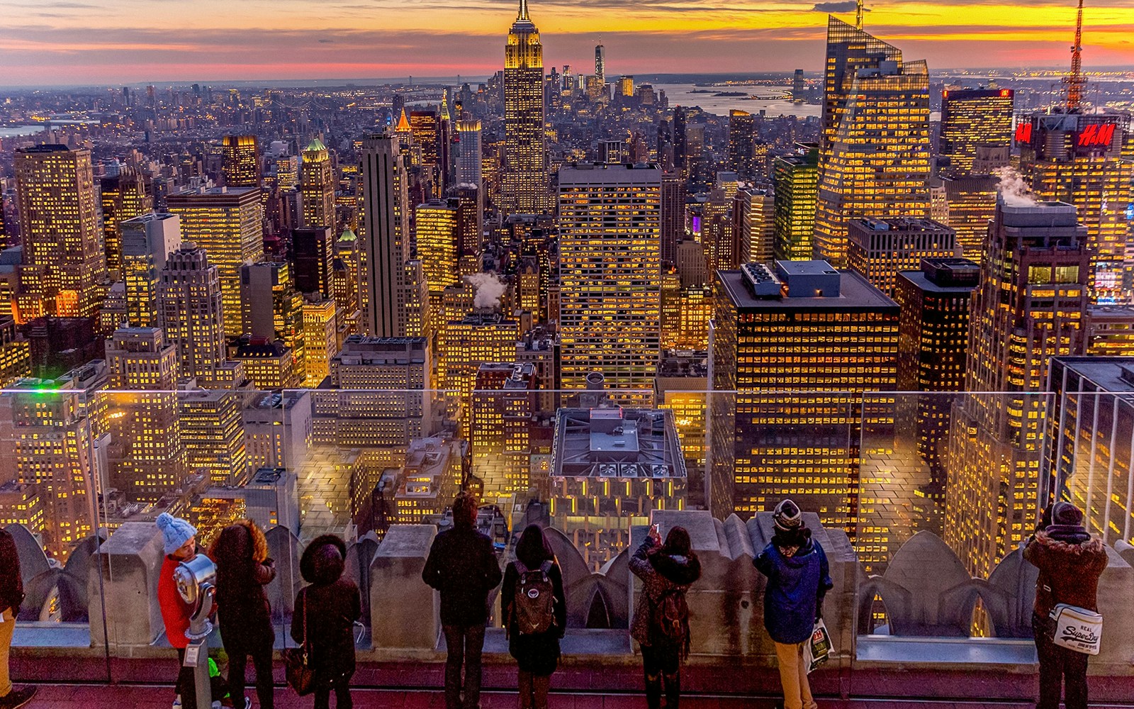 Visitors viewing Manhattan skyline at dusk from Top of the Rock, Rockefeller Center, New York.