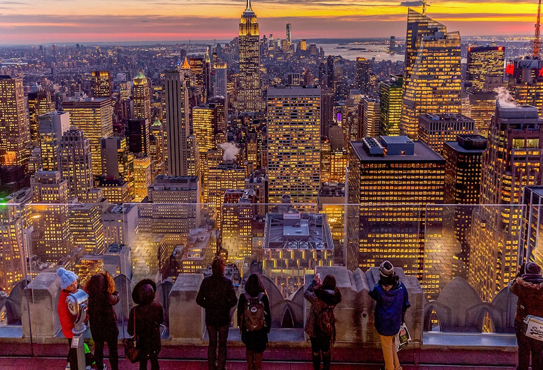 Visitors viewing Manhattan skyline at dusk from Top of the Rock, Rockefeller Center, New York.