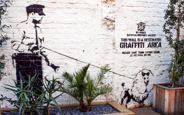 Street art of a policeman and dog on Brick Lane, London, featured on the food tour.