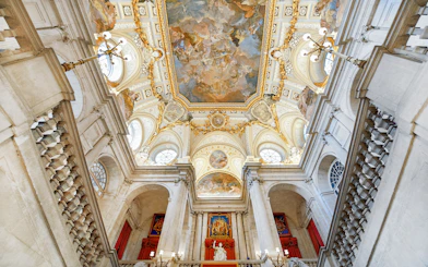Royal Palace of Madrid interior with ornate ceiling and grand staircase.