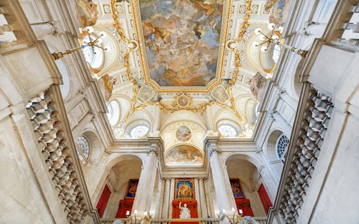 Royal Palace of Madrid interior with ornate ceiling and grand staircase.
