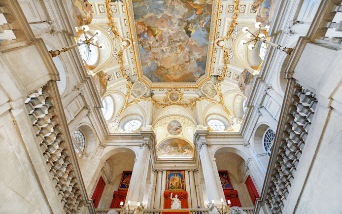 Royal Palace of Madrid interior with ornate ceiling and grand staircase.