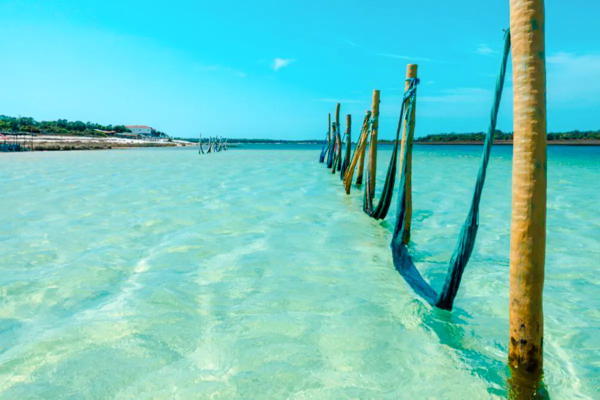 Water hammocks in clear waters of Jericoacoara, Brazil, with distant shoreline.