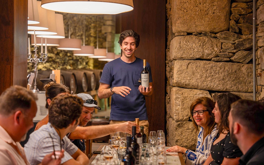 Tourists with guide tasting wine in Douro wine cellar.